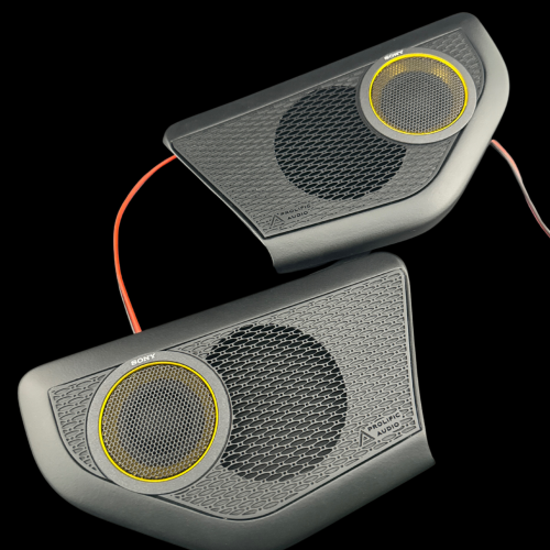 Two black audio speakers with yellow accents and mesh grilles connected by wires.