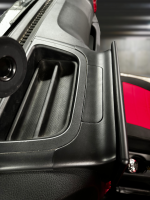 Close-up of a black plastic console with a smooth surface and red accents in a vehicle interior.