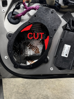 Cut speaker mounting bracket with exposed wiring and components inside a vehicle door.