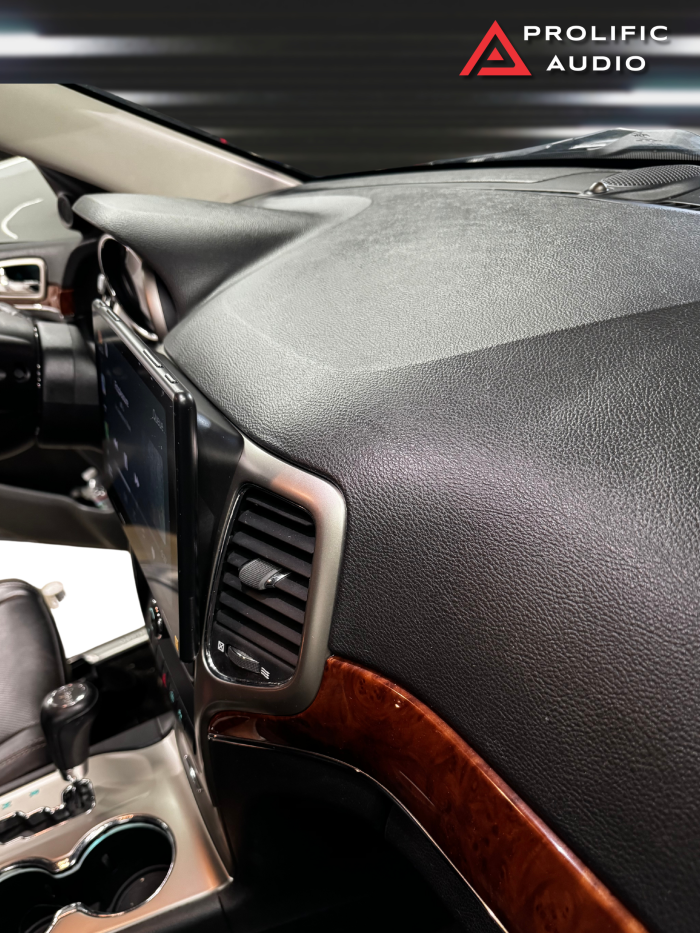 Angled view of the dashboard in a 2011-2013 Jeep Grand Cherokee, featuring the Sony XAV-9500ES radio installed with Prolific Audio's DIY kit. The image highlights the sleek integration of the radio with the custom bezel, ensuring a precise fit with the vehicle's woodgrain trim and maintaining a professional, factory-like appearance.