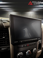 Sony car stereo display mounted in a vehicle dashboard with control buttons below.