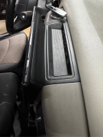 Close-up view of a car's dashboard area with a textured panel and control buttons.