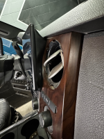 Interior view of a car dashboard showing an incomplete installation of a stereo system with wood paneling.