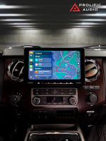 Car dashboard displaying a large touchscreen with navigation map and audio controls in a vehicle interior.