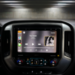 Dark car interior with a glossy touchscreen infotainment system displaying Too Sweet by Hozier; Prolific Audio logo sits in the top-right corner of the image.